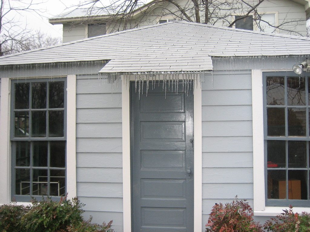 White painted cottage with large paned windows and a grey front door